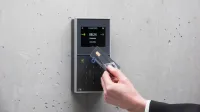 A businessman uses a secure card reader access system against a concrete wall.