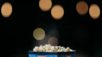 Una vista de cerca de palomitas en un cubo temático con fondo de bokeh de película.
