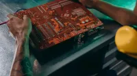 Primer plano de un técnico que trabaja en una placa de circuito en un entorno industrial.