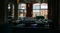 Un interior de restaurante con poca luz que cuenta con un juego de copas de vino limpias y un ambiente acogedor.