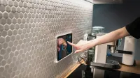 A modern kitchen with a touchscreen smart home control panel integrated into a hexagon-patterned wall.