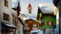 Encantadora escena invernal de una calle de pueblo alpino cubierta de nieve con coloridas casas y una torre de la iglesia.