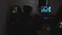 Un profesional que analiza datos en múltiples monitores en un cuarto oscuro, destacando los temas de ciberseguridad.