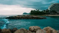 A stunning ocean view at Ko Olina, Hawaii with a resort and rocky shore under dramatic skies.