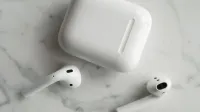 High-quality image of wireless earbuds and charging case on marble surface, showcasing modern technology.