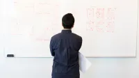 Hombre analizando el diagrama de flujo del diseño en la pizarra en un entorno de oficina profesional.