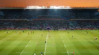 Emocionante juego de rugby desplegando bajo una impresionante puesta de sol en un gran estadio.