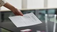 Close-up de una mano sosteniendo una papeleta en interiores, simbolizando la democracia y los derechos civiles.