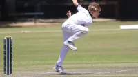 Joven jugador de críquet en acción en un día soleado, capturado en medio de los bowls con un enfoque intenso.