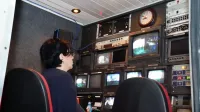 Un profesional en una sala de control de transmisión de televisión con múltiples pantallas y equipos.