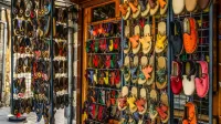 Vibrant handmade shoes on display in an outdoor market with various patterns and colors.