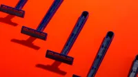 Blue disposable razors arranged neatly on a vivid orange background, creating a striking contrast.
