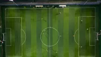 Dynamic aerial shot capturing a soccer match on a vibrant green field at night.