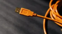 Foto macro detallada de un conector de cable USB naranja con enfoque en la textura.