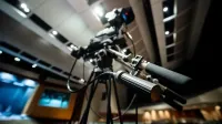 From below of modern professional video camera with wires placed on tripod in studio on blurred background