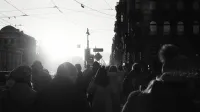 Silhouettes of people walking in a city street during sunrise with a vintage, moody tone.