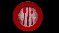 Placa roja artística con patrones de azúcar de tenedor y cuchara sobre fondo negro.