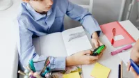 Niño usando una calculadora mientras estudia en un escritorio con útiles escolares, centrándose en las matemáticas.