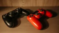 Imagen detallada de controladores de juego rojo y negro sobre una superficie de madera.