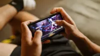 Una persona que juega un videojuego móvil en un teléfono inteligente, centrándose en el estilo de vida de los juegos y la tecnología.