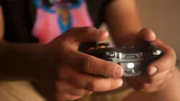 Una persona que sostiene un controlador de juego inalámbrico en el interior, enfatizando los juegos relajados.