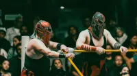 Los luchadores enmascarados compiten en un emocionante partido de Lucha Libre ante una audiencia comprometida.