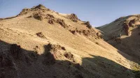Vista pintoresca de erizado monta con arena marrón bajo el cielo azul despejado a la luz del día