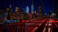 A breathtaking night view featuring the New York City skyline and iconic Brooklyn Bridge illuminated in vibrant colors.