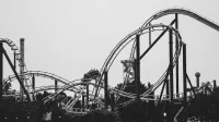 Imagen monocromática de una montaña rusa con pistas en bucle en un parque de atracciones al aire libre.