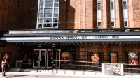 Exterior view of a brick theater showcasing current movie advertisements in an urban setting.