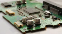 Detailed view of a green circuit board featuring capacitors and microchips.