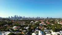 Impresionante vista aérea del horizonte de la ciudad de Perth y casas suburbanas bajo el cielo azul claro.