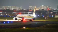 Un avión de Singapore Airlines en la pista por la noche en medio de las luces de la ciudad y las luces del aeropuerto.