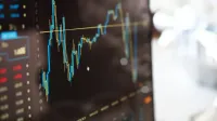 Detailed view of financial trading graphs on a monitor, illustrating stock market trends.