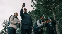 Cuatro amigos disfrutando de una caminata, capturando el momento con selfies en un entorno escénico al aire libre.