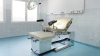 Sala de examen ginecológica brillante con silla ajustable y luz de techo en un centro médico.