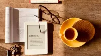 Desde arriba de té compuesto con galleta y libro con lector en mesa de madera con gafas y auriculares