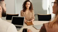 Una mujer con traje de negocios participa en una entrevista de trabajo, mostrando profesionalismo y ambiente de oficina moderno.