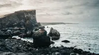 Impresionante vista de los escarpados acantilados costeros de Islandia y el vasto Océano Atlántico Norte durante un día nublado.