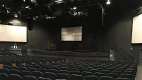 Rows of comfortable empty seats in modern theater hall with stage and screens