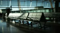 Zona de estar desierta en el aeropuerto con luz solar que fluye a través de grandes ventanas. Ambiente tranquilo y silencioso.