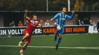 Two soccer players in action during a competitive match on a green field.