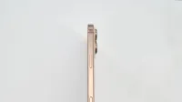 Minimalist side view of a gold smartphone on white background.