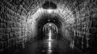 Explore el túnel atmosférico de paredes de piedra iluminado con poca intensidad para obtener un efecto dramático.