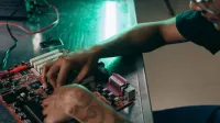 Close-up of person assembling a computer motherboard, showcasing a tattooed arm and tech innovation.