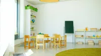 Un salón de clases de jardín de infantes colorido y bien iluminado con sillas, mesas y materiales educativos.