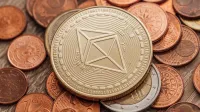 Primer plano de una moneda Ethereum física en un montón de monedas fiat.