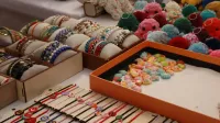 Vibrant display of handmade bracelets and crocheted keychains at a market stall.