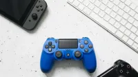 Vista superior de varios controladores de juegos y un teclado en una superficie blanca.