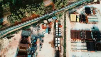 Una toma aérea detallada que muestra una instalación de almacenamiento industrial al aire libre con materiales metálicos y rodeado de árboles.